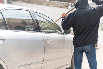 Car thief trying to break into a car .Masked man breaking into car with crowbar.