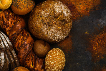Assortment of fresh baked bread and buns on kitchen table. Space for text. Top view