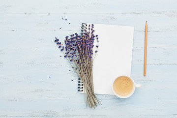 Morning cup of coffee, clean notebook and lavender flower on blue background top view. Woman...