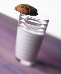 Glass of milk with cookie balanced on top