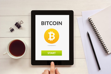 Bitcoin concept on tablet screen with office objects on white wooden table. All screen content is designed by me. Flat lay