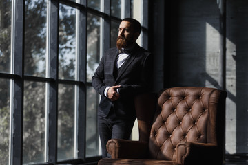 Handsome caucasian businessman dressed in the suit near the window in the loft interior studio