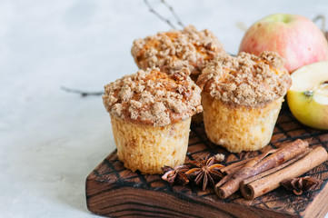 Apple cinnamon crumble muffins on a wooden board. White stone background. Close up and copy space.
