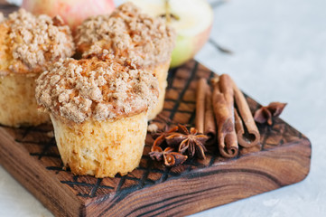 Apple cinnamon crumble muffins on a wooden board. White stone background. Close up and copy space.