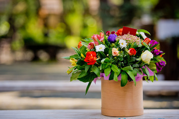 A beautiful gift bouquet in a wooden vase on a wooden bench. Wedding decorations.