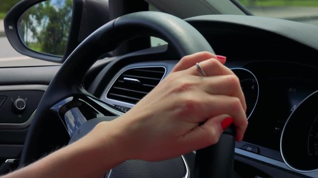 Young attractive blond woman drives a car - road in countryside - detail of hand on the steering wheel 