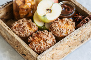 Apple cinnamon crumble muffins, salted caramel sauce, spices in a wooden box. White stone background. Close up and copy space.