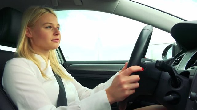 Young attractive blond woman drives a car - closeup