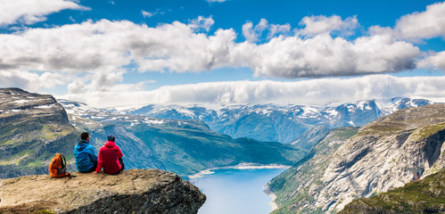 Couple sitting against amazing nature view on the way to Trolltunga. Location: Scandinavian...