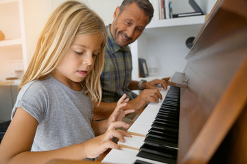 Little girl with teacher playing piano