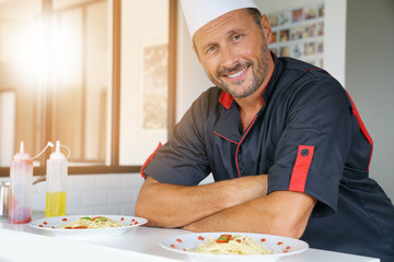 Portrait of chef in uniform standing in private kitchen