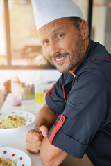 Portrait of chef in uniform standing in private kitchen