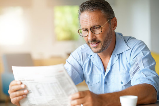 Portrait of mature man with eyeglasses reading newspaper