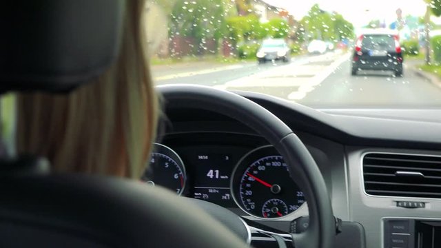 Young attractive blond woman drives a car in the city in rainy day - closeup 