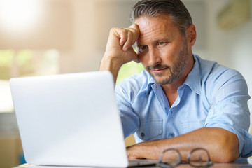 Mature man working on laptop computer at home
