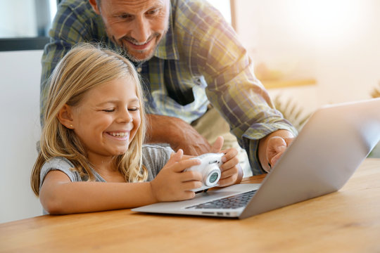 Little girl with daddy looking at pictures on computer