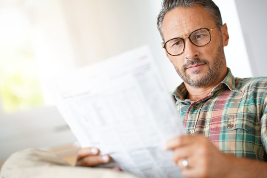 Mature man with eyeglasses reading newspaper