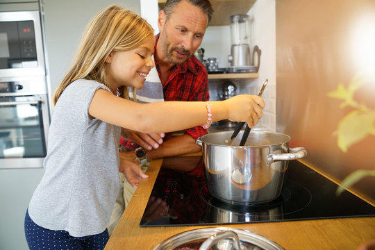 Daddy with daughter cooking together in home kitchen