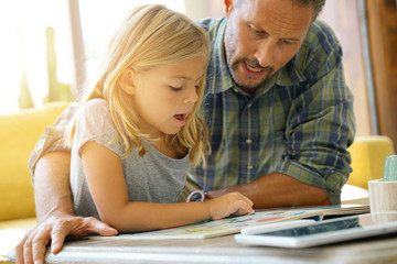 Father and child reading book at home