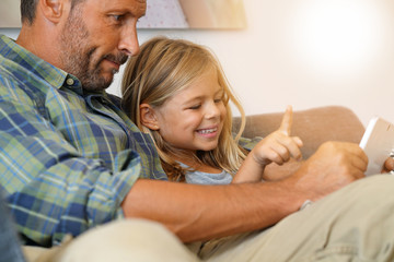 Daddy with little girl connected on digital tablet