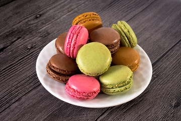 a plate of colorful macaroons on a wooden background