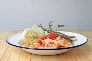 Papaya Salad with Carrot, Lentils, Tomato, Dried Shrimp, Chilli, in a White plate on wooden background. Thai style food.