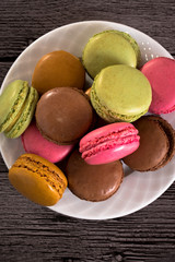 a plate of colorful macaroons on a wooden background