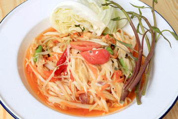 Papaya Salad with Carrot, Lentils, Tomato, Dried Shrimp, Chilli, in a White plate on wooden background. Thai style food.