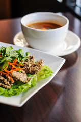 Nam Tok Spicy Beef Salad, Char-broiled tender slices of beef mixed with red onion, green onions, roasted rice, cilantro, chili powder & citrus leaves.