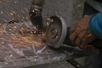 worker cuts a metal pipe by means of the abrasive tool