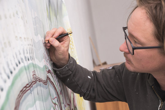Artist is working with a pensil on his art piece in his work shop