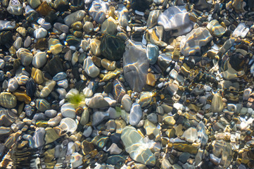 sea pebble beach with multicoloured stones, waves with foam