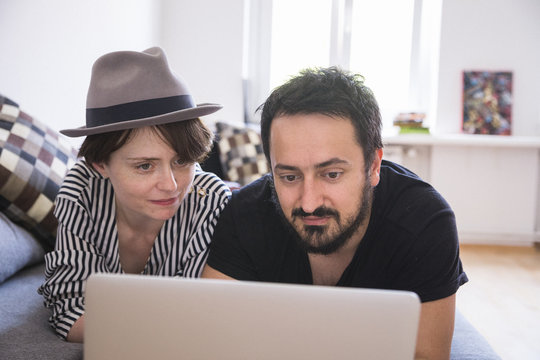 Young couple relax on the couch in front of the computer