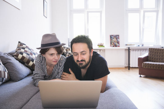 Young couple relax on the couch in front of the computer