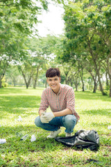 Obraz premium Young man crouching to waste and picking it up in bin bag