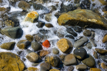 rocky sea shore with pebble beach, waves with foam