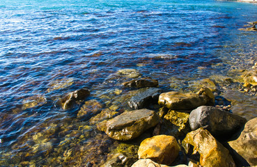 rocky sea shore with pebble beach, waves with foam