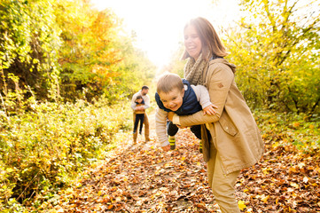 Beautiful young family on a walk in autumn forest.