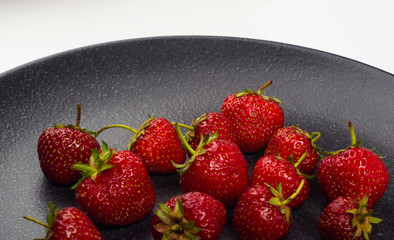 fresh ripe strawberries on black ceramic plate