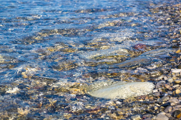 sea pebble beach with multicoloured stones, waves with foam