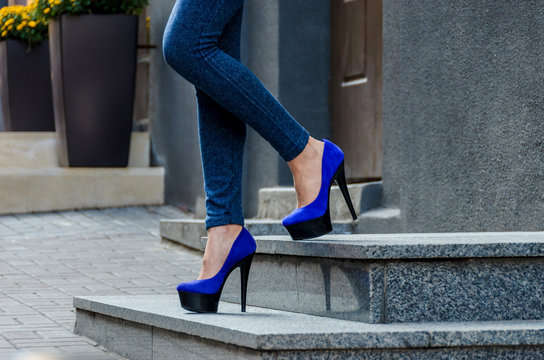Beautiful slender female legs in tight jeans and blue velvet high-heeled shoes