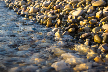 Obraz premium sea pebble beach with multicoloured stones, waves with foam