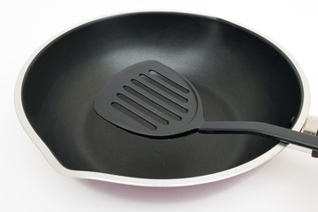 black plastic flipper use in frying pan on white background