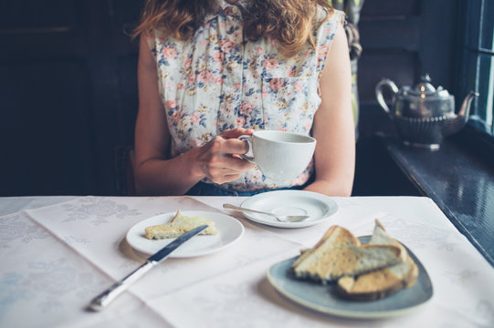 Young woman drinking coffee and eating toast