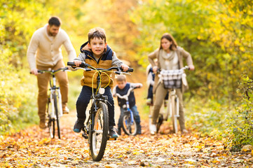 Fototapeta na wymiar Young family in warm clothes cycling in autumn park