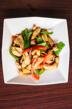 Stir-Fried Cashew Chicken, Slices of chicken breast stir-fried with cashew nuts, peapods, pineapple, onions, tomato ,and bell peppers.