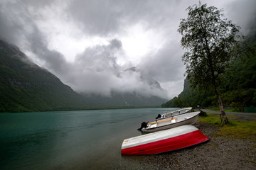 Obraz premium The Norwegian landscape with a boat on lake against mountains.