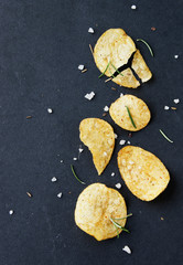 Chips with salt and rosemary on black background