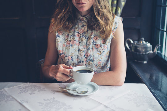 Woman at table by window drinking coffee