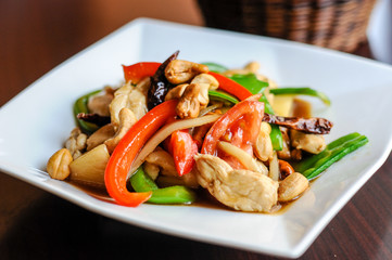 Stir-Fried Cashew Chicken, Slices of chicken breast stir-fried with cashew nuts, peapods, pineapple, onions, tomato ,and bell peppers.